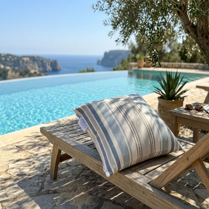 Wooden lounge chair with a striped cushion by a pool with ocean view