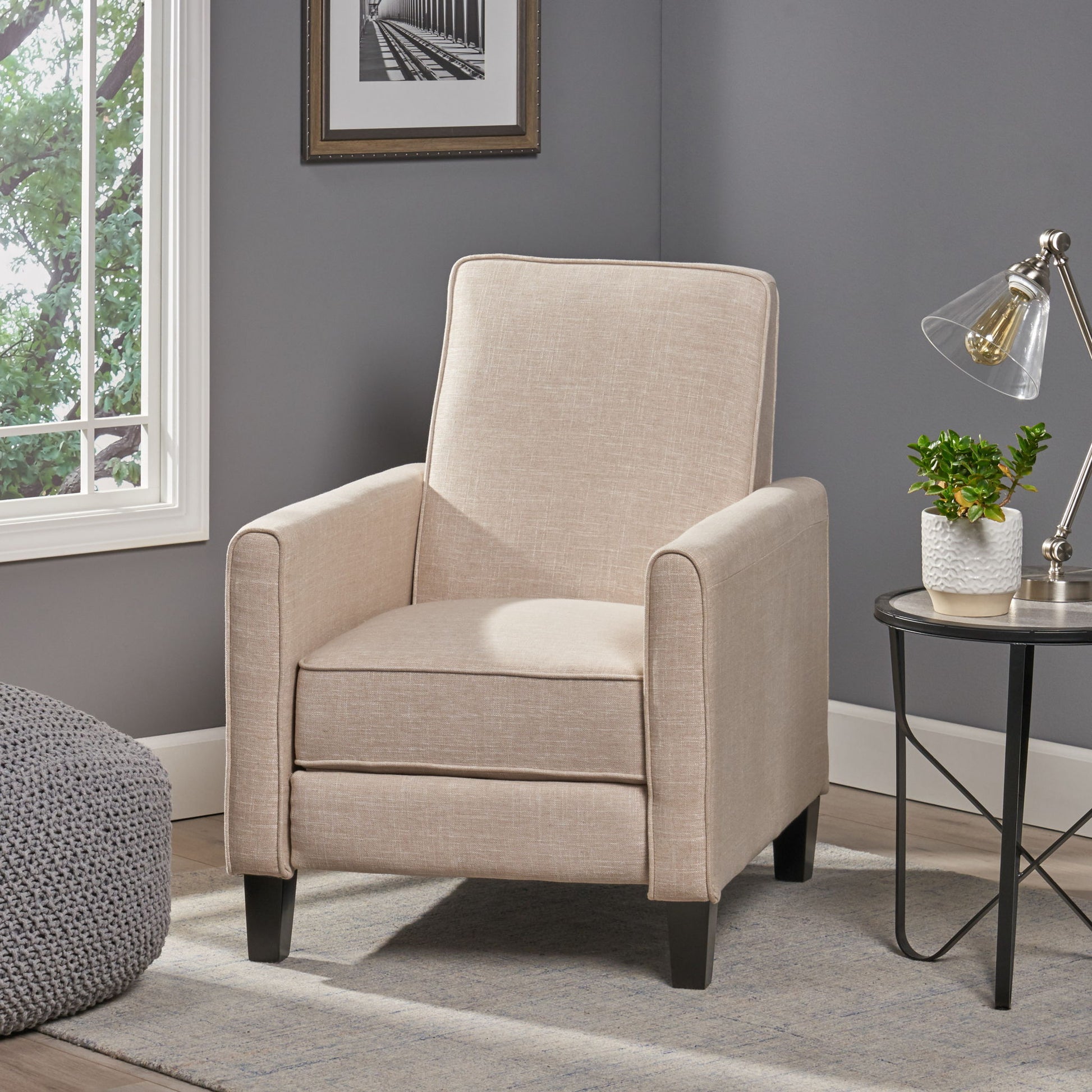 Beige armchair in a living room setting with a side table and lamp.